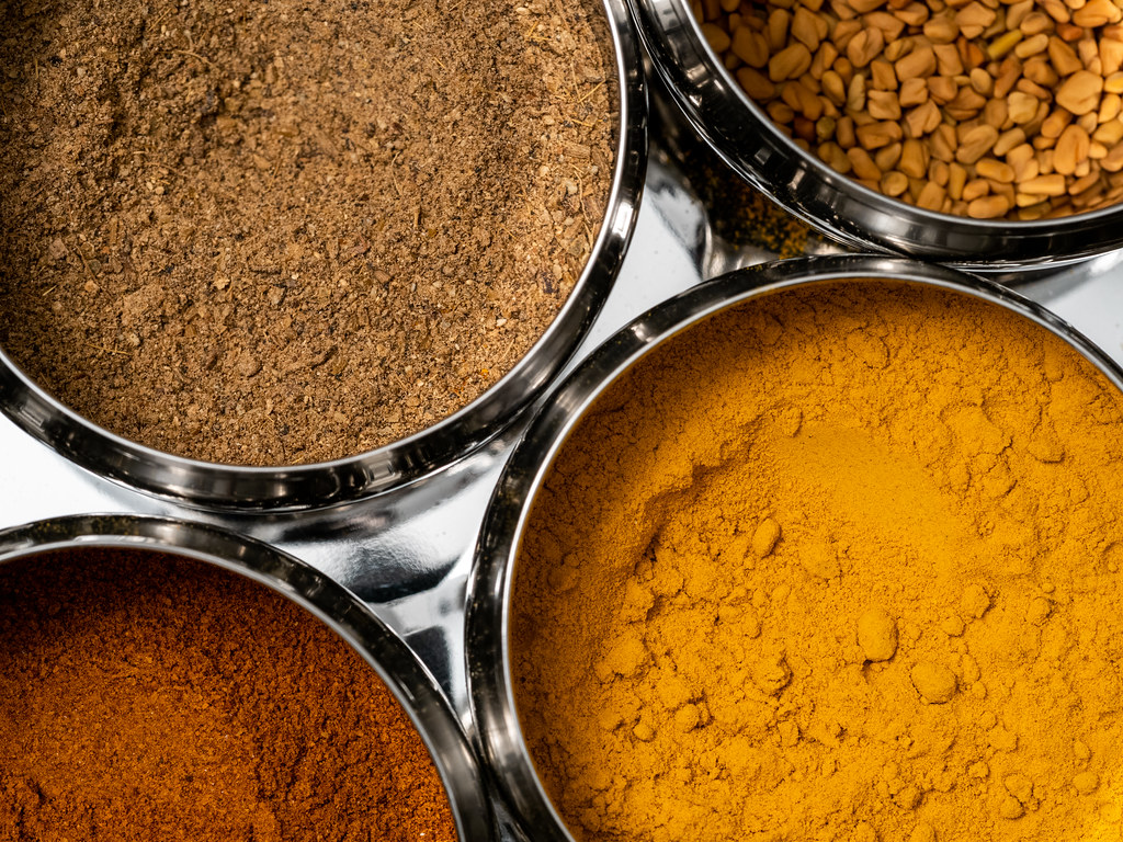 Assorted Indian whole and ground spices arranged in bowls