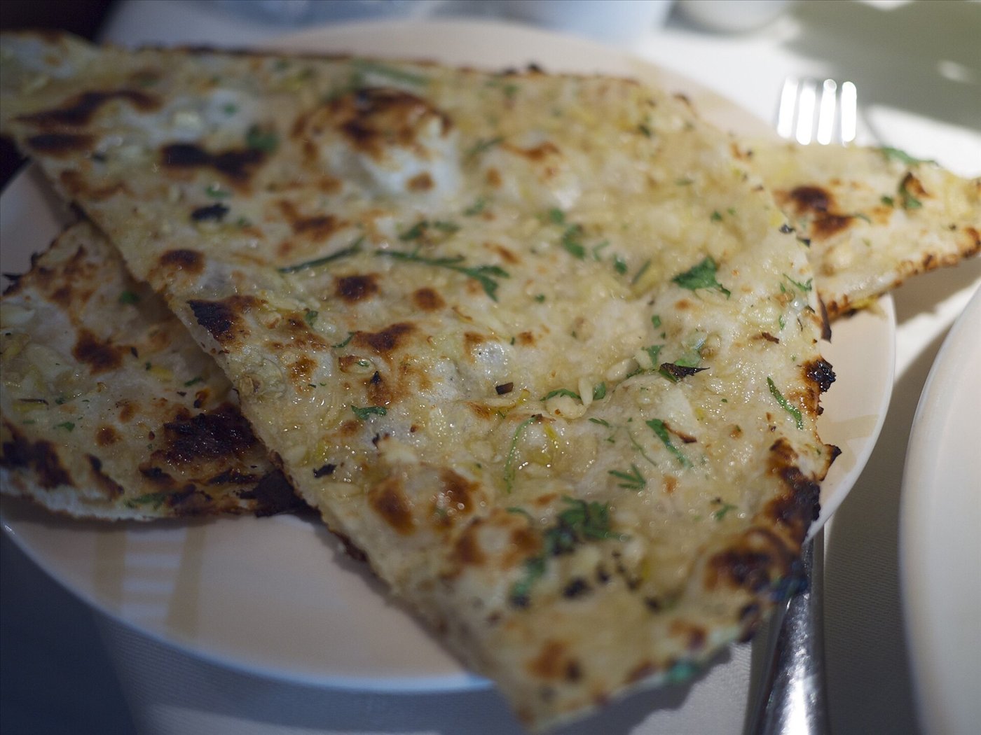 Garlic naan bread topped with chopped garlic and coriander