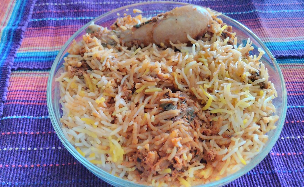 A steaming serving of Hyderabadi chicken dum biryani garnished with fried onions, mint and boiled egg